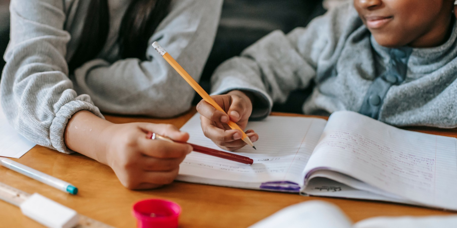 Two school-age students writing together while practicing math word problems.