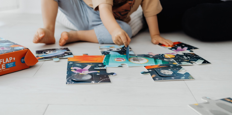 Two children assembling a large jigsaw puzzle together.
