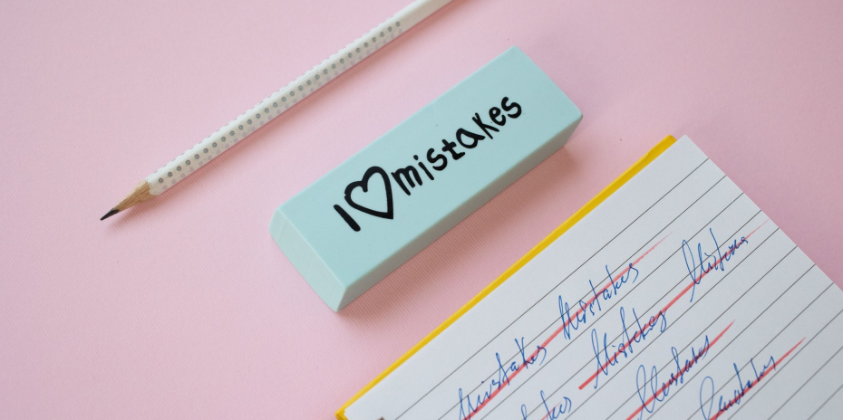 A pencil and an eraser labeled I love mistakes on a pink desk.